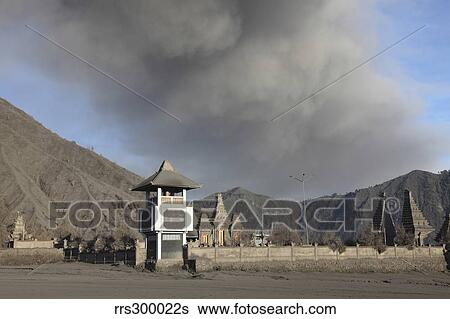 Stock Photograph - Ash cloud passing over temple at foot of Mount Bromo Volcano, Tengger Caldera, Java, Indonesia.. Fotosearch