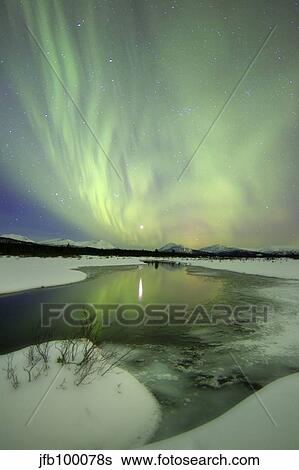 Stock Photograph - Aurora borealis over a creek by Fish Lake, Yukon, Canada.. Fotosearch