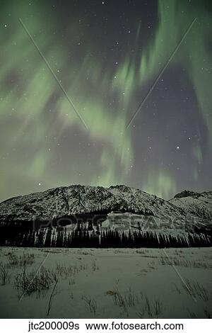 Stock Photograph - Aurora borealis over mountain, Annie Lake, Yukon, Canada.. Fotosearch