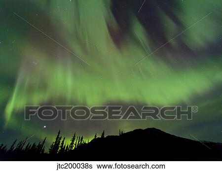 Stock Photograph - Aurora borealis over mountain, Marsh Lake, Yukon, Canada.. Fotosearch