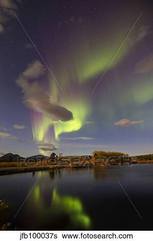 Stock Photograph - Aurora borealis with moonlight at Fish Lake, Yukon, Canada.. Fotosearch