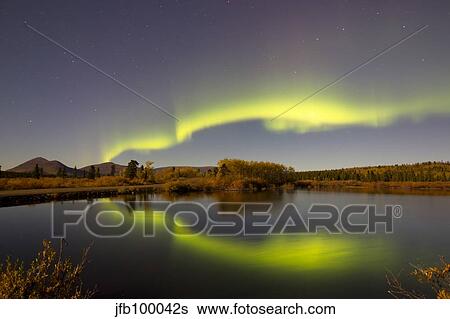Stock Photograph - Aurora borealis with moonlight at Fish Lake, Yukon, Canada.. Fotosearch