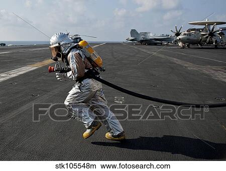 Aviation Boatswain's Mate carries a fire hose during a fire drill. View Large Photo Image Picture - Aviation Boatswain's Mate carries a fire hose during a fire drill.. Fotosearch