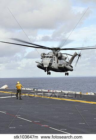 Aviation Boatswain's Mate directs a CH-53 Sea Stallion helicopter onto the flight deck of USS Essex. View Large Photo Image Picture - Aviation Boatswain's Mate directs a CH-53 Sea Stallion helicopter onto the flight deck of USS Essex.. Fotosearch