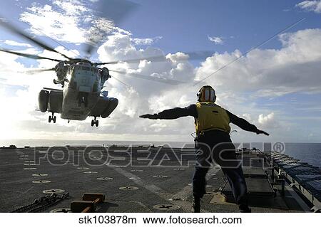 Aviation Boatswain's Mate directs a CH-53E Super Stallion onto the flight deck of USS Harpers Ferry. View Large Photo Image Picture - Aviation Boatswain's Mate directs a CH-53E Super Stallion onto the flight deck of USS Harpers Ferry.. Fotosearch