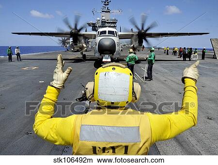 Aviation Boatswain's Mate directs a C-2A Greyhound onto a catapult. View Large Photo Image Picture - Aviation Boatswain's Mate directs a C-2A Greyhound onto a catapult.. Fotosearch