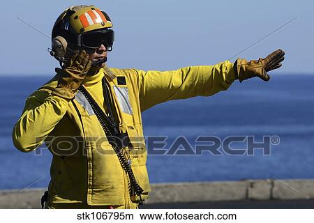Aviation Boatswain's Mate directs an aircraft on the flight deck. View Large Photo Image Picture - Aviation Boatswain's Mate directs an aircraft on the flight deck.. Fotosearch