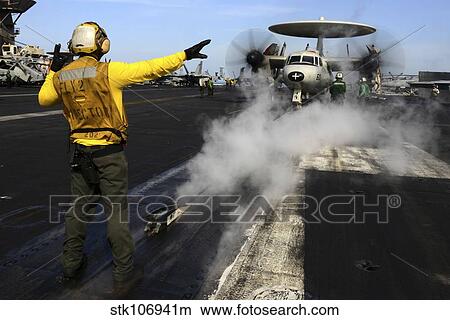 Aviation Boatswain's Mate directs an E-2C Hawkeye on the flight deck. View Large Photo Image Picture - Aviation Boatswain's Mate directs an E-2C Hawkeye on the flight deck.. Fotosearch