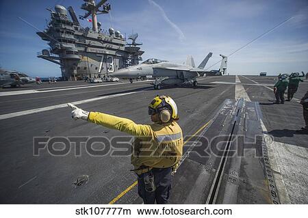 Aviation Boatswain's Mate directs an F/A-18E Super Hornet. View Large Photo Image Picture - Aviation Boatswain's Mate directs an F/A-18E Super Hornet.. Fotosearch