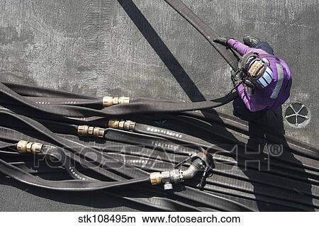 Aviation Boatswain's Mate gathers a fuel hose on the flight deck. View Large Photo Image Picture - Aviation Boatswain's Mate gathers a fuel hose on the flight deck.. Fotosearch