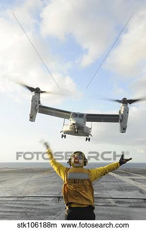 Aviation Boatswain's Mate signals an MV-22 Osprey to land. View Large Photo Image Picture - Aviation Boatswain's Mate signals an MV-22 Osprey to land.. Fotosearch
