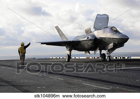 Aviation Boatswain's Mate signals the pilot to lift an F-35B Lightning II off the flight deck. View Large Photo Image Picture - Aviation Boatswain's Mate signals the pilot to lift an F-35B Lightning II off the flight deck.. Fotosearch