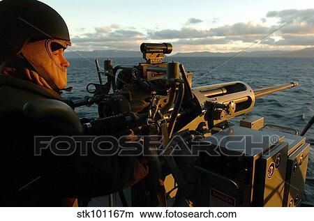 Aviation Ordnanceman mans a MK-38 25mm machine gun aboard USS Peleliu. View Large Photo Image Picture - Aviation Ordnanceman mans a MK-38 25mm machine gun aboard USS Peleliu.. Fotosearch