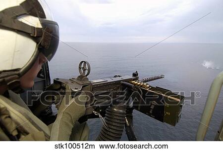 Picture - Aviation Warfare Systems Operator fires a. 50 caliber machine gun out of an SH-60B helicopter.. Fotosearch