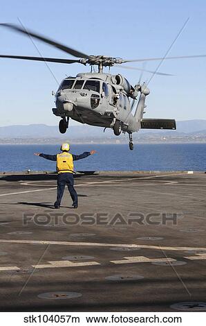 Boatswain's Mate directs an MH-60S Sea Hawk helicopter on the flight deck of USS Comstock View Large Photo Image Picture - Boatswain's Mate directs an MH-60S Sea Hawk helicopter on the flight deck of USS Comstock. Fotosearch