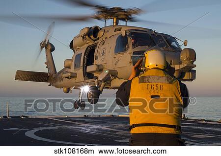 Boatswain's Mate guides an MH-60R Sea Hawk onto the flight deck. View Large Photo Image Picture - Boatswain's Mate guides an MH-60R Sea Hawk onto the flight deck.. Fotosearch