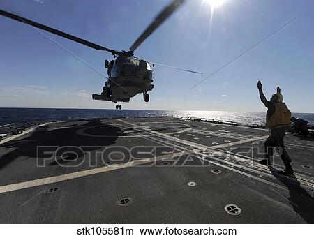 Boatswain's Mate signals the pilots of an SH-60B Sea Hawk helicopter. View Large Photo Image Picture - Boatswain's Mate signals the pilots of an SH-60B Sea Hawk helicopter.. Fotosearch