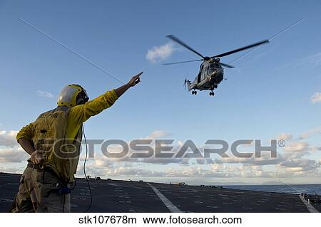 Boatswain's Mate signals to a French Armee De Terre SA 380 Puma helicopter. View Large Photo Image Picture - Boatswain's Mate signals to a French Armee De Terre SA 380 Puma helicopter.. Fotosearch
