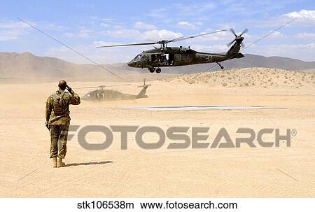 Brigade aviation officer salutes as a UH-60 Black Hawk helicopter lifts off. View Large Photo Image Picture - Brigade aviation officer salutes as a UH-60 Black Hawk helicopter lifts off.. Fotosearch