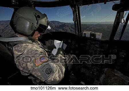Picture - CH-47 Chinook pilot refers to his checklist while in flight.. Fotosearch