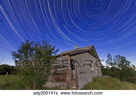 Stock Photograph - Circumpolar star trails above an old farmhouse in Alberta, Canada.. Fotosearch