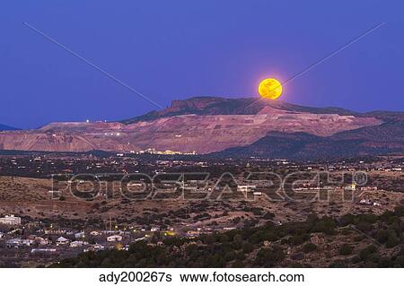 Stock Photograph - Copper moon rising over the Santa Rita Copper Mine in New Mexico.. Fotosearch