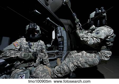 Crew Chief sits in the doorway of a UH-60 Black Hawk while medic sits on the hoist. View Large Photo Image Picture - Crew Chief sits in the doorway of a UH-60 Black Hawk while medic sits on the hoist.. Fotosearch