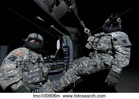 Crew Chief sits in the doorway of a UH-60 Black Hawk while medic sits on the hoist. View Large Photo Image Picture - Crew Chief sits in the doorway of a UH-60 Black Hawk while medic sits on the hoist.. Fotosearch