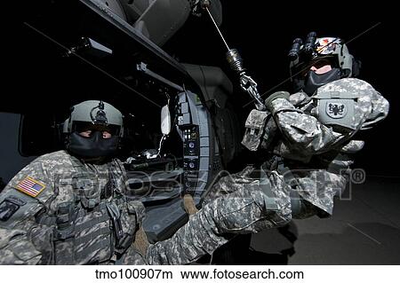 Crew Chief sits in the doorway of a UH-60 Black Hawk while medic sits on the hoist. View Large Photo Image Picture - Crew Chief sits in the doorway of a UH-60 Black Hawk while medic sits on the hoist.. Fotosearch