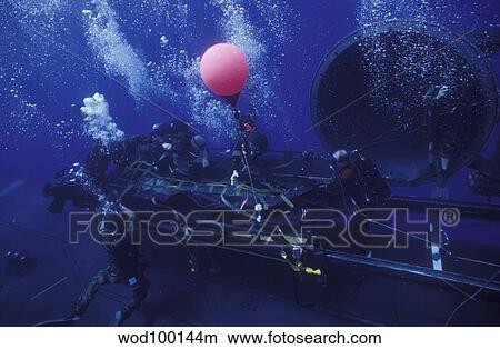 Picture - Crewmen disconnect the cargo straps from the combat rubber raiding craft on the dry deck shelter.. Fotosearch
