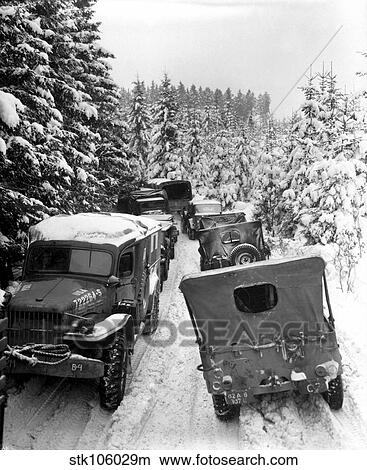 Deep snow banks on a narrow road halt military vehicles in Belgium. View Large Photo Image Picture - Deep snow banks on a narrow road halt military vehicles in Belgium.. Fotosearch