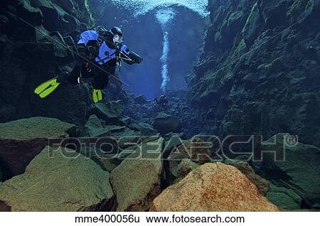 Stock Photograph - Dry suit divers in gin clear waters of Silfra Crack, Iceland.. Fotosearch