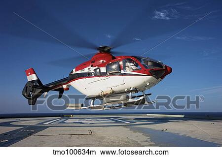 Eurocopter EC135 utility helicopter on the helipad of an oil rig. View Large Photo Image Picture - Eurocopter EC135 utility helicopter on the helipad of an oil rig.. Fotosearch