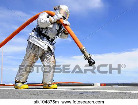 Firefighter carries a charged hose across the flight deck of USS Denver. View Large Photo Image Picture - Firefighter carries a charged hose across the flight deck of USS Denver.. Fotosearch