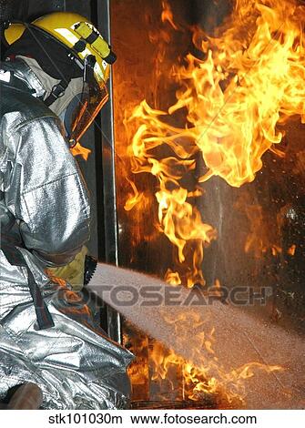 Firefighter extinguishes a simulated structural fire. View Large Photo Image Picture - Firefighter extinguishes a simulated structural fire.. Fotosearch