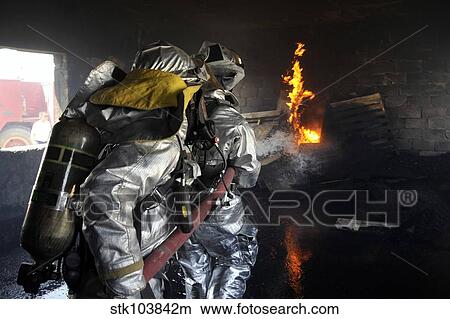 Firefighters extinguish a fire in a training room during live burn training. View Large Photo Image Picture - Firefighters extinguish a fire in a training room during live burn training.. Fotosearch