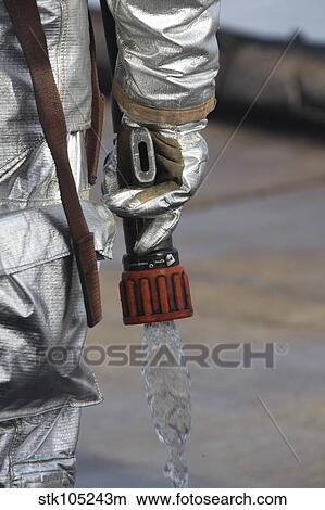 Firefighting Marine tests his hand line nozzle to check the water flow. View Large Photo Image Picture - Firefighting Marine tests his hand line nozzle to check the water flow.. Fotosearch
