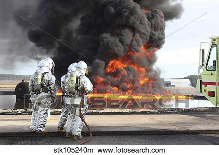 Picture - Firefighting Marines watch as a training fire builds intensity.. Fotosearch
