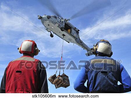 Flight deck personnel wait for supplies from an MH-60S Sea Hawk. View Large Photo Image Picture - Flight deck personnel wait for supplies from an MH-60S Sea Hawk.. Fotosearch