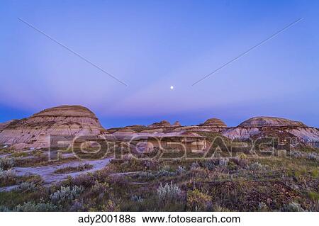 Gibbous moon and crepuscular rays over Dinosaur Provincial Park, Canada. View Large Photo Image Stock Photograph - Gibbous moon and crepuscular rays over Dinosaur Provincial Park, Canada.. Fotosearch