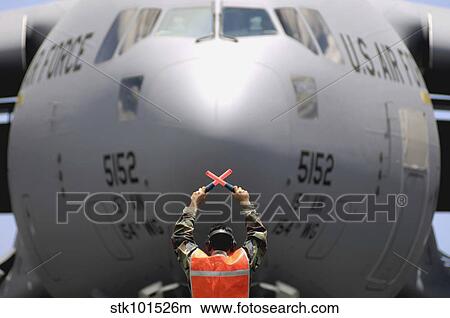 Ground crewmember marshals a C-17 Globemaster III to its parking spot. View Large Photo Image Picture - Ground crewmember marshals a C-17 Globemaster III to its parking spot.. Fotosearch