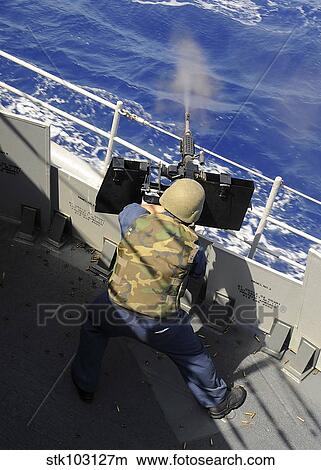 Gunners Mate firing a. 50 caliber machine gun aboard the guided-missile cruiser USS Vella Gulf. View Large Photo Image Picture - Gunners Mate firing a. 50 caliber machine gun aboard the guided-missile cruiser USS Vella Gulf.. Fotosearch