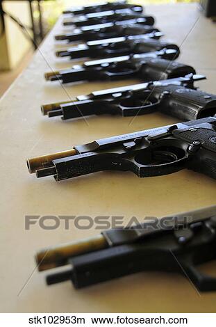 Handguns lined up on a table. View Large Photo Image Picture - Handguns lined up on a table.. Fotosearch