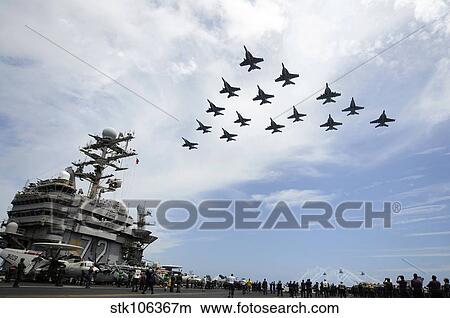Helicopters fire flares as jets fly in formation above the flight deck of USS Abraham Lincoln. View Large Photo Image Picture - Helicopters fire flares as jets fly in formation above the flight deck of USS Abraham Lincoln.. Fotosearch