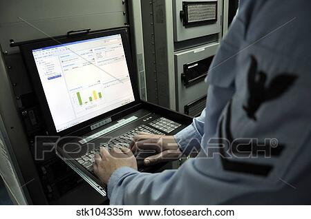 Information Systems Technician monitors network activity from a laptop. View Large Photo Image Picture - Information Systems Technician monitors network activity from a laptop.. Fotosearch