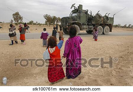 Picture - Iraqi children wave to an American convoy.. Fotosearch