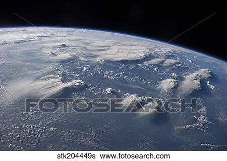 Stock Photograph - Late afternoon sunlight casts long shadows from thunderhead anvils down onto southern Borneo.. Fotosearch