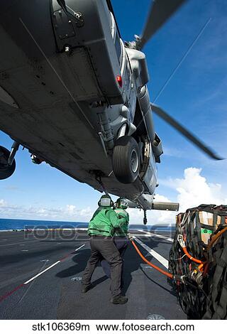 Logistics Specialists hook cargo onto an MH-60S Sea Hawk helicopter. View Large Photo Image Picture - Logistics Specialists hook cargo onto an MH-60S Sea Hawk helicopter.. Fotosearch