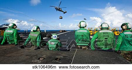 Picture - Logistics specialists stand by as an MH-60S Sea Hawk delivers supplies.. Fotosearch