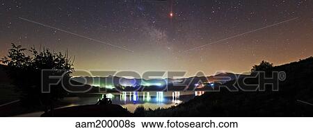 Stock Photograph - Lunar eclipse and Milky Way above Taleqan Lake, Iran.. Fotosearch